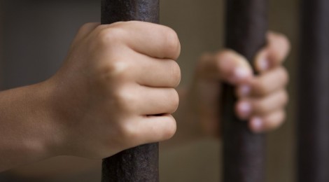 Hands (of a young child) clutching prison bars - Selective focus.