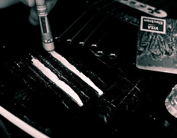 Lines of cocaine on a table with a rolled up bill being used to snort them.