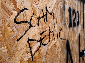 An exposed particle board wall with "SAMDEMIC" spray painted on it.