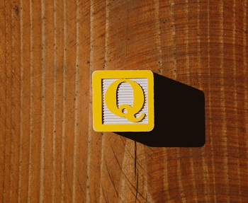 A yellow child's letter block with the letter "Q" on it.