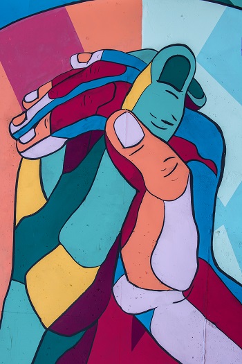 Artistic drawing of two multicoloured hands holding each other.