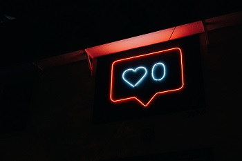 A neon sign displays an Instagram heart with zero likes