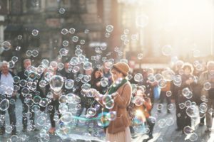 Woman smiling and holding her hands out, surrounded by bubbles.