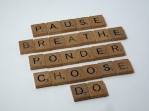 Wooden 'Scrabble' tiles spelling out the words: PAUSE, BREATHE, PONDER, CHOOSE, DO.