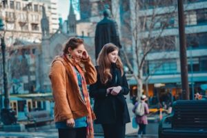 Two young women walking through a city centre.
