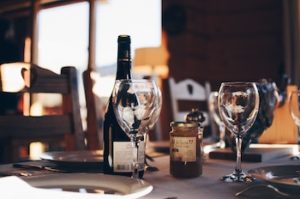 Wine glass and wine bottle sits on table lit by candlelight