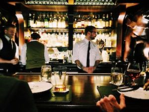 Bartender stands behind bar and watches patrons