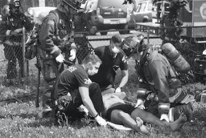 black and white photo of first responders helping civilian