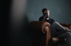 colour photo of stressed man sitting on couch