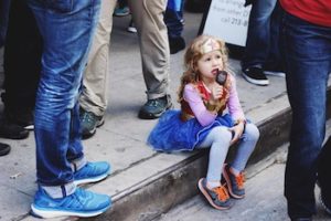 Young woman sits on curb and eats ice cream cone with a Wonder Woman costume on