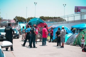 Colour photo of immigrants in tents being approached my police