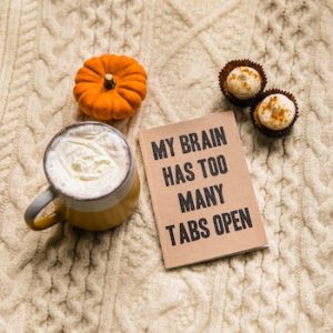Fall themed coffee with mini pumpkin and two cupcakes with a sign that reads "my brain has too many tabs open" 
