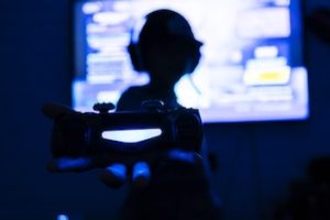 silhouette of man holding a videogame controller in front of pixelated TV screen 