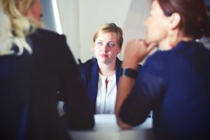 colour picture of a woman sitting in a meeting with two other women