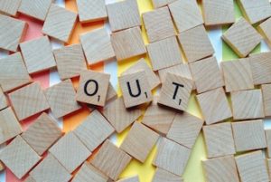 Scrabble pieces spelling the word "Out" with rainbow background
