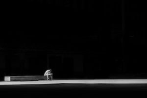black and white distance photo of a man sitting on a bench