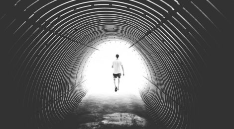 A person walks away, disappearing into a tunnel of white light.