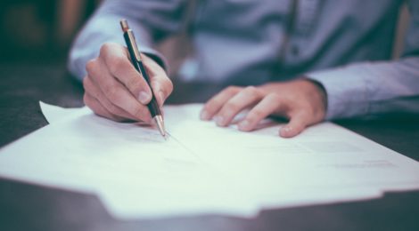 A man signing legal documents at a table with a pen.