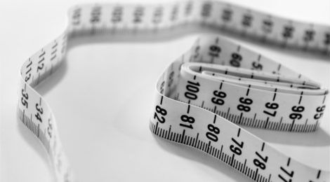 Loose measuring tape on a white surface.