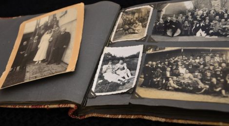 An old family photo album, open, revealing the yellowed and black-and-white photos within.