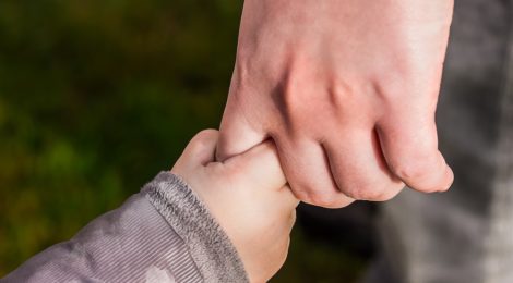 Child's hand holding parent's finger.