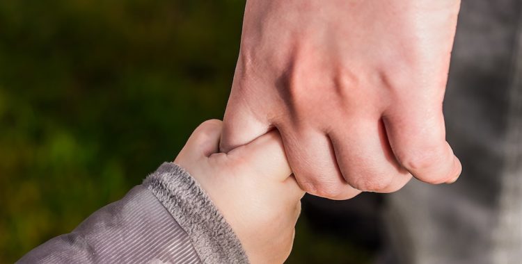 Child's hand holding parent's finger.