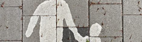 White painted silhouette of parent and child hand-in-hand on a grey brick sidewalk.