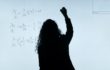 Silhouette of a woman writing mathematical equations on a whiteboard.