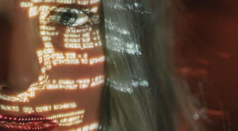 Up close image of a woman's eye with a shadow of computer code over her face
