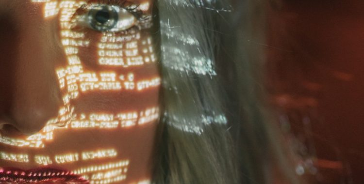 Up close image of a woman's eye with a shadow of computer code over her face
