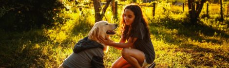 girl and her dog sit in the forest with sunset