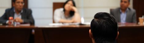 man sits i front of panel in the a court room