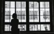 Black and white image of a woman looking out a window