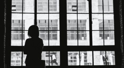 Black and white image of a woman looking out a window