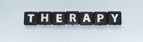the words therapy in black and white scrabble pieces
