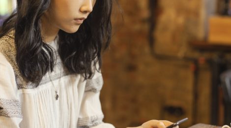 woman sitting at table looking at her phone