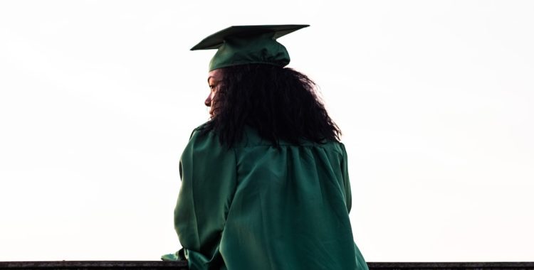 Graduate Student in Green Robe Looks Over Ledge